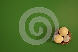 Eggs in a basket on a green background. White chocolate and white speckled eggs