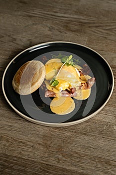 Eggs Benedict with bacon and ham on a wooden table