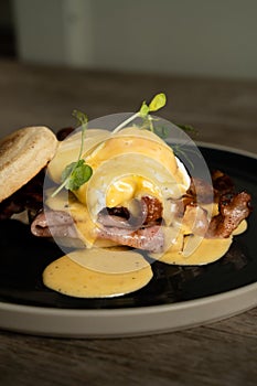 Eggs Benedict with bacon and ham on a wooden table