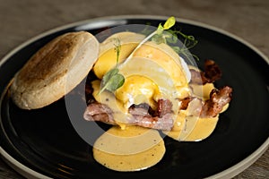 Eggs Benedict with bacon and ham on a wooden table