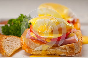 Eggs benedict on bread with tomato and ham