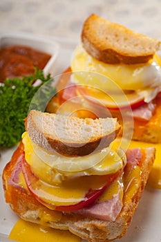 Eggs benedict on bread with tomato and ham