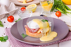 Eggs Benedict for breakfast on white wooden background