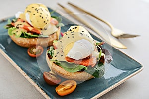 Eggs Benedict with salad leafs, salmon and fresh cherry tomato