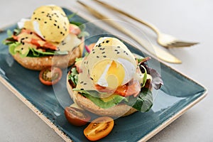 Eggs Benedict with salad leafs, salmon and fresh cherry tomato