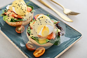 Eggs Benedict with salad leafs, salmon and fresh cherry tomato