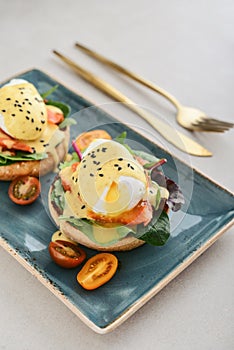 Eggs Benedict with salad leafs, salmon and fresh cherry tomato