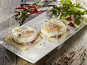 Eggs Benedict and salad on white plate