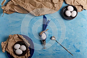 Eggs on brown paper and blue plate. Easter bunny made from egg and polka dot napkin ears, spoon, silver egg cup