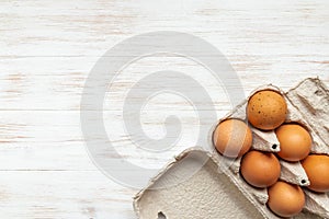 Eggs in carton bow on wooden background with copy space