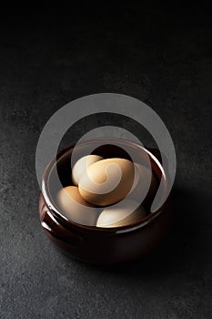 Eggs in a ceramic pot on black rustic background