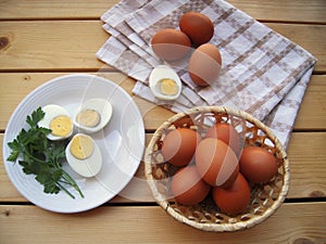 Eggs cut on a plate, in the basket and on the kitchen towel on a wooden table, rustic styl