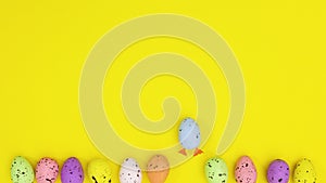 Eggs in different colors move on bottom of yellow theme and two with legs move up. Stop motion