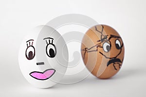 Eggs with drawn faces on white background. Concept of jealousy