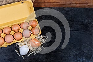 Eggs in egg tray and beside on dark surface, background photo