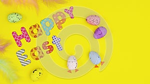 Eggs and feathers appear and Happy Easter text write on yellow theme. Stop motion