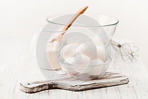 Eggs, flour, and a Cup for the test on a white table. Place for text.