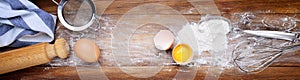 Eggs, flour and tools for egg pasta or other culinary preparations on a wooden background. Top view, space for text.