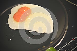 Eggs in fry pan, each egg with double yolks, double egg yolks fried in pan, close up of fried egg