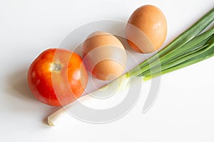 Eggs, green onion and tomato on white background. Ingredients for breackfast