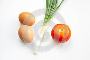 Eggs, green onion and tomato on white background. Ingredients for breackfast