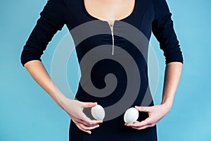 Eggs in the hands of a sexy girl in a black dress. The concept of ovaries, months and pms photo