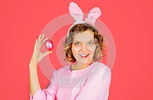 Eggs hunt. Happy Easter. Smiling Woman in bunny ears with pink egg. Rabbit girl. Spring holidays.