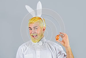 Eggs hunt. Smiling man in rabbit ears with Easter egg. Bearded man in bunny ears. Easter rabbit man with painted Easter