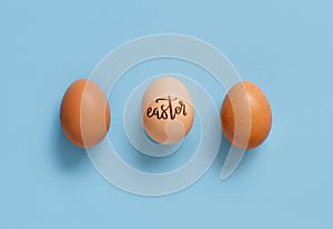 Eggs with inscription EASTER over light blue background