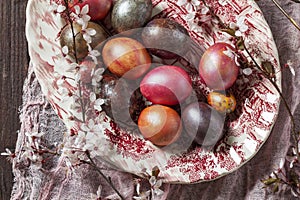 Eggs painted in different colors and covered with mother-of-pearl, and blossoming plum branches. Easter concept.