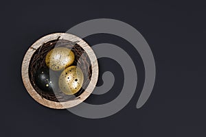 Eggs painted gold and black. Overhead of nest containing three egg. Minimal Easter concept with copy space for text.