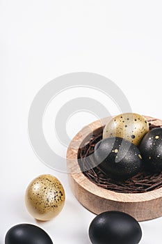 Eggs painted gold and black. Overhead of nest containing egg. Minimal Easter concept with copy space for text.