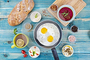 Eggs in Pan with Bread and Hummus and Labneh with Cup of Tea with Limon. On Blue Wood Surface, Perfect Breakfast Meal, Fried eggs