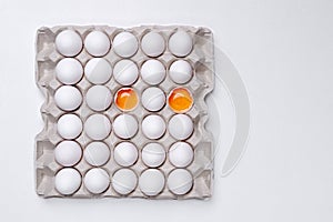 Eggs in paper tray with two cracked open on the white backgrou
