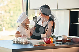 Eggs and pepper. Mother with her daughter are preparing food on the kitchen