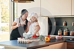 Eggs and pepper. Mother with her daughter are preparing food on the kitchen