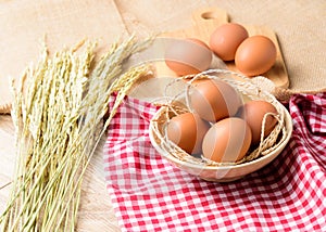 The eggs are placed in a white bowl and placed on a red Scottish plaid with ear of rice or spike