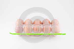 Eggs in plastic box with green adhesive tape on white background