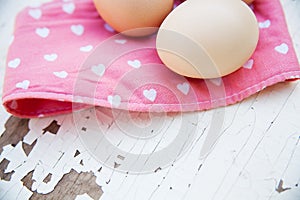 Eggs on tablecloth over wooden background