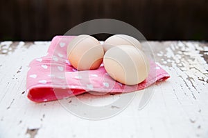 Eggs on tablecloth over wooden background