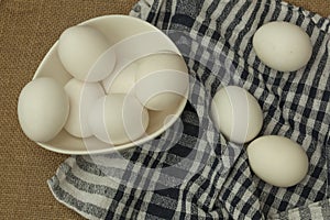 Eggs in a white bowl with napkin on table mat.