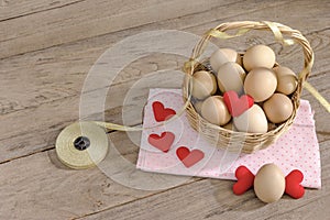 Eggs in a wicker basket with heart-shaped on wooden table