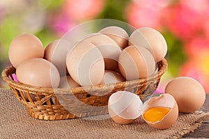 Eggs in a wicker basket on a wooden board with blurred garden background