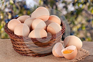 Eggs in a wicker basket on a wooden board with blurred garden background