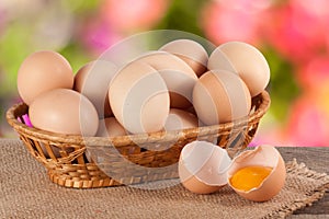 Eggs in a wicker basket on a wooden board with blurred garden background