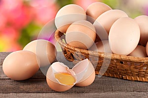 Eggs in a wicker basket on a wooden board with blurred garden background