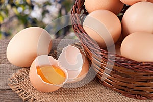 Eggs in a wicker basket on a wooden board with blurred garden background