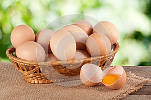 Eggs in a wicker basket on a wooden board with blurred garden background