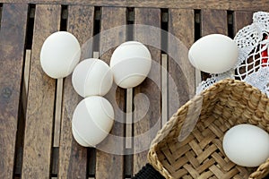 Eggs on wooden table and basket