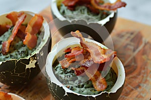 eggshell containing spinach foam and crispy bacon